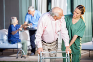 Pflegeheldering mit älterem Herren und Rolator
